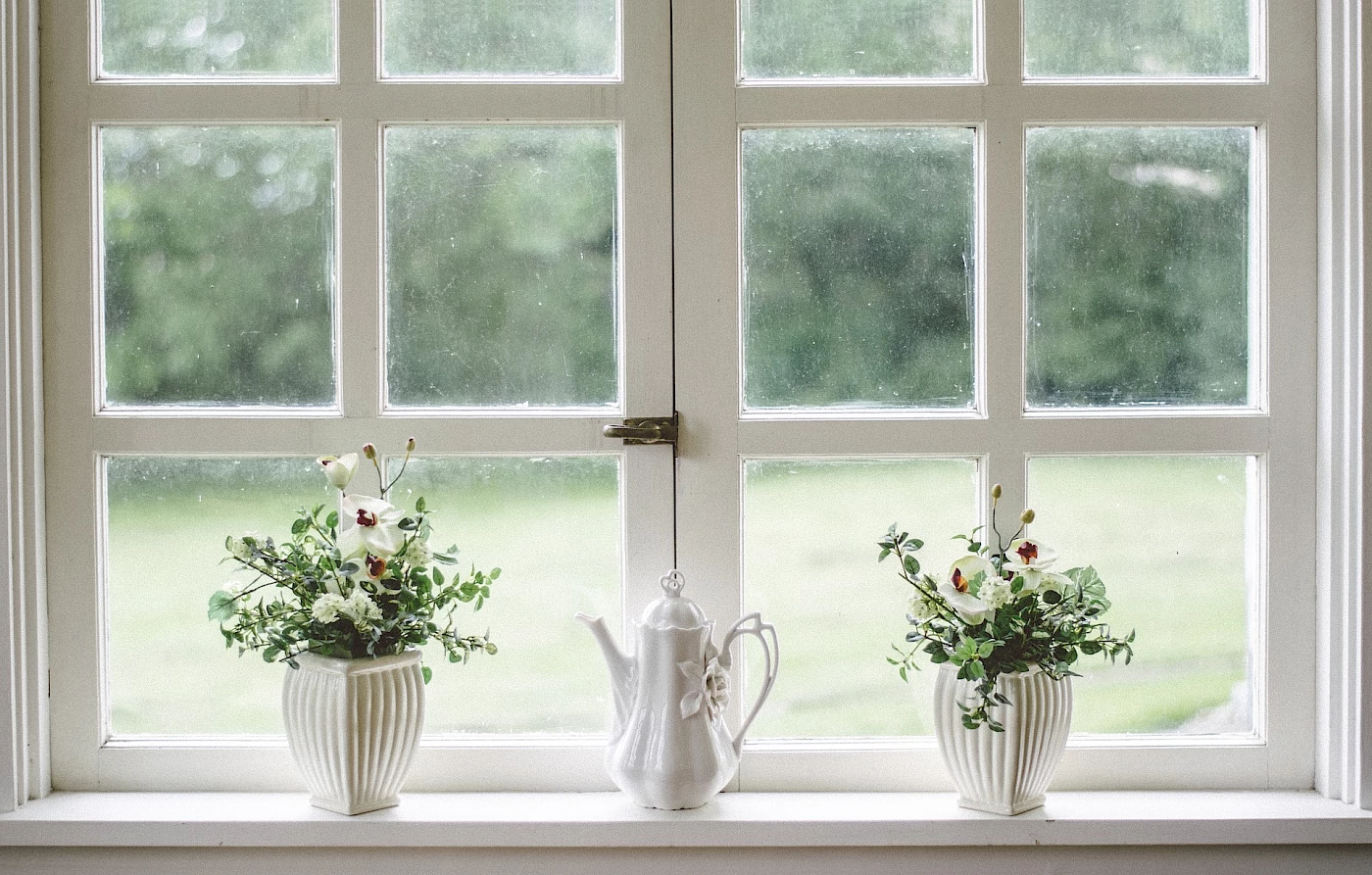 Hallin Löfgren Juristbyrå - Ett fönster med två vaser fyllda med färgglada blommor arrangerade på fönsterbrädan.