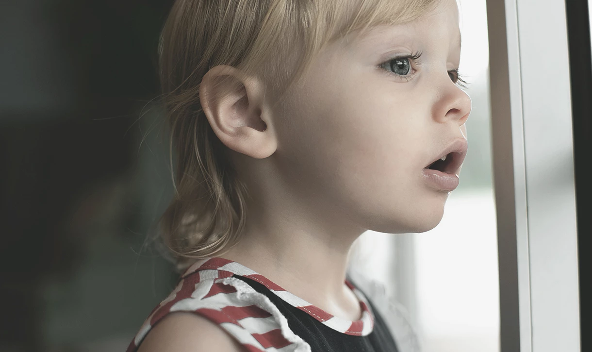 Hallin Löfgren Juristbyrå - En ung flicka tittar ut genom ett fönster.